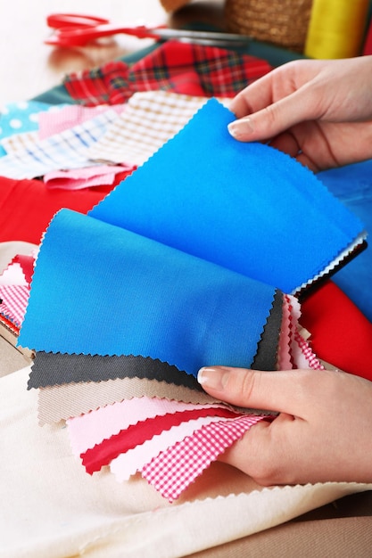 Colorful fabric samples in female hands on wooden table background