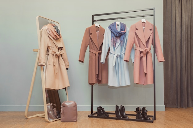 Colorful female coats and neckpieces on the rail.