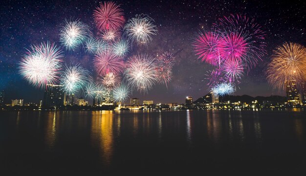 Colorful fireworks display over city on the beach Firework celebration sparkling in midnight sky sea