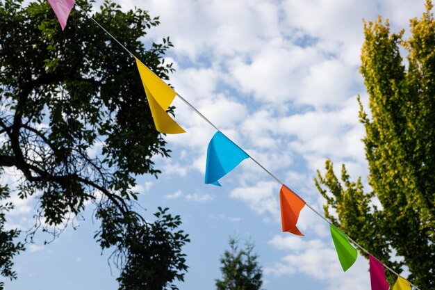 A colorful flags hangs in the sky above a tree line.