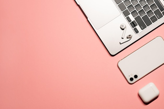 Colorful flat lay shot of a silver grey laptop computer white smartphone wireless earphones