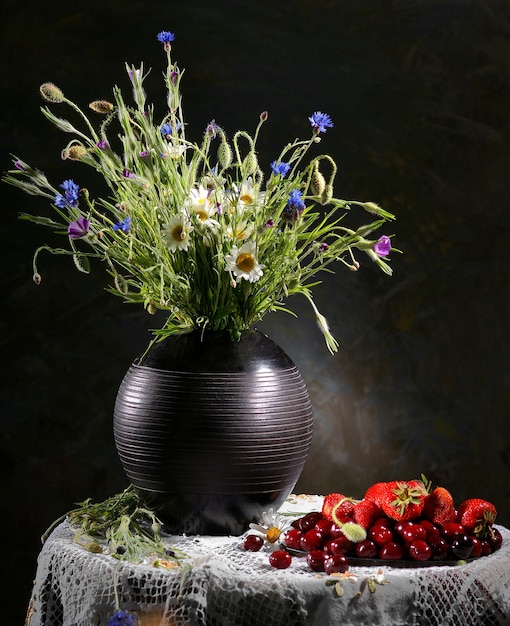 Colorful flower arrangement centerpiece in black vase and fruits on a salver on a dark abstract background