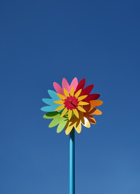 A colorful flower with a red center is on a stick