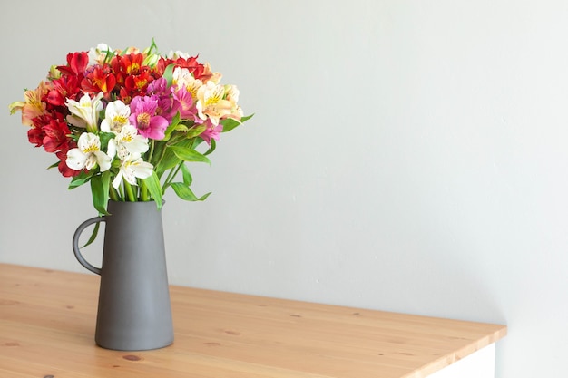 Colorful flowers in a cement vase on a wooden table