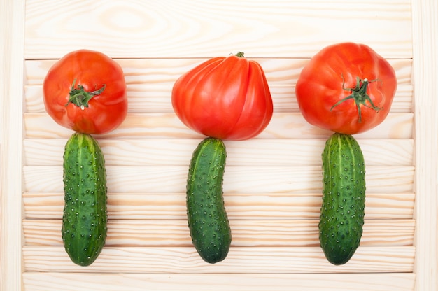 トマトとキュウリで作られた木製の背景に色とりどりの花。健康食品のコンセプトです。