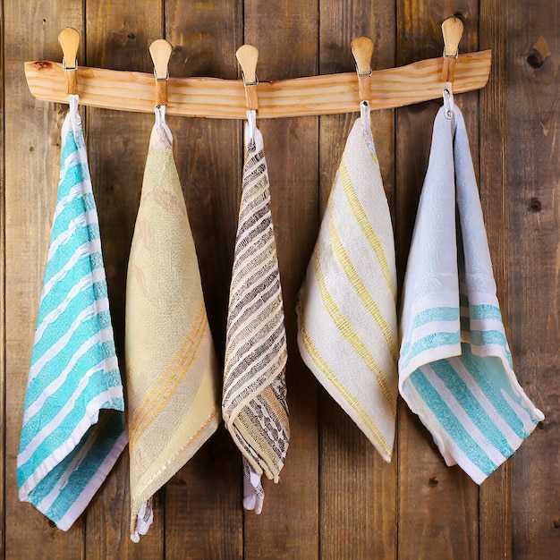 Colorful folded kitchen towels hanging on a rope on a wooden background