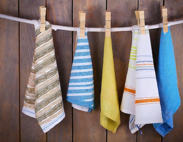 Colorful folded kitchen towels hanging on a rope on a wooden background