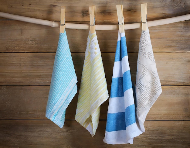 Colorful folded kitchen towels hanging on a rope on a wooden background