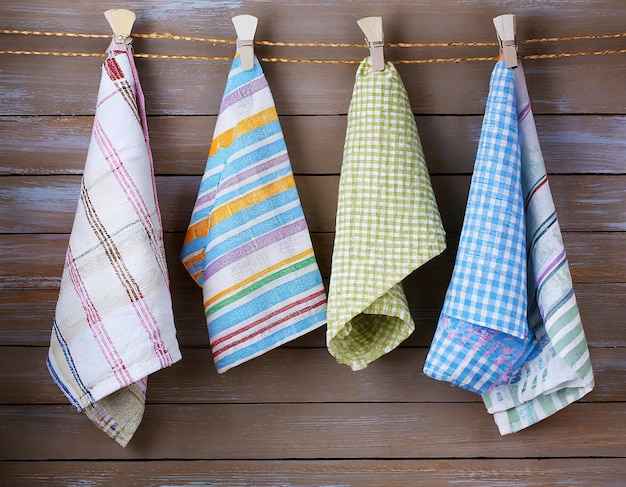 Colorful folded kitchen towels hanging on a rope on a wooden background