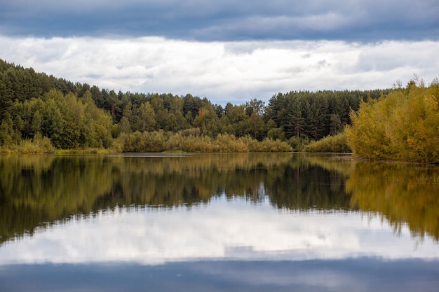 Colorful foliage tree reflections in calm pond water on a beautiful autumn day. A quiet and beautiful place to relax.