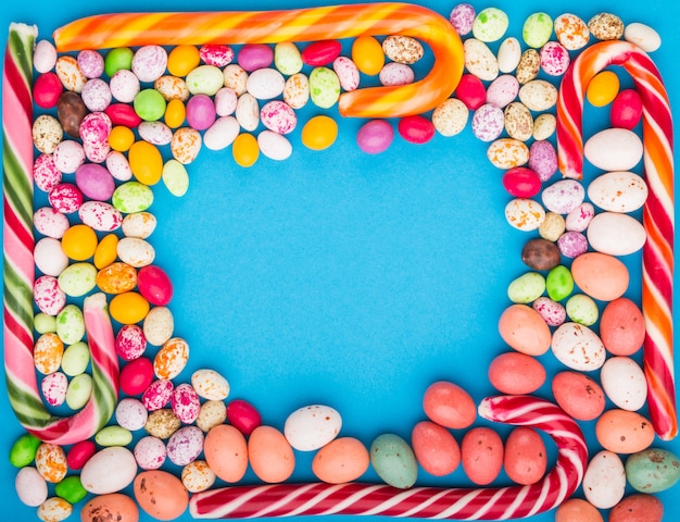 Colorful frame of multicolored candies on blue 