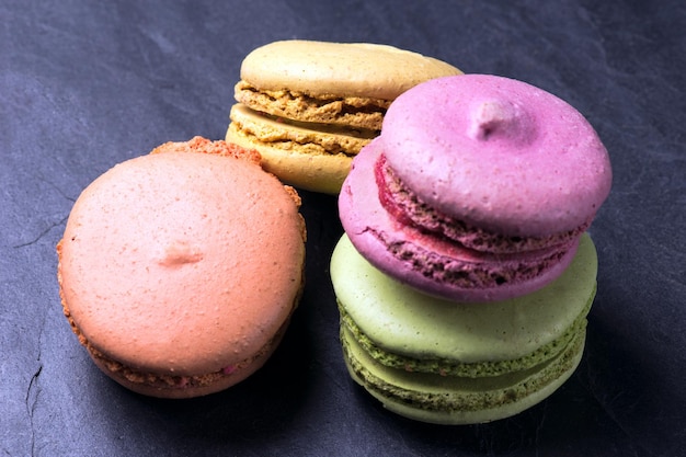 Colorful French macarons on a black background.