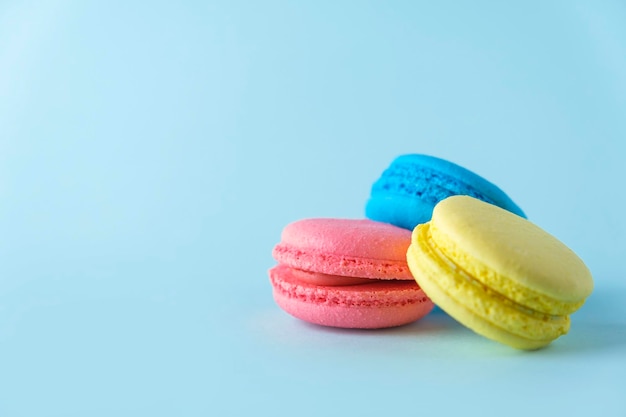 Colorful french macarons cookies macaroons on blue background Dessert vegetarian sweets close up