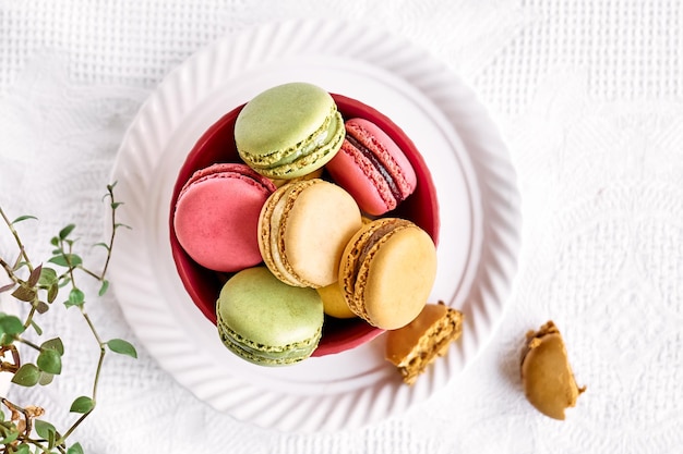 Photo colorful french macarons in pink bowl on white tablecloth