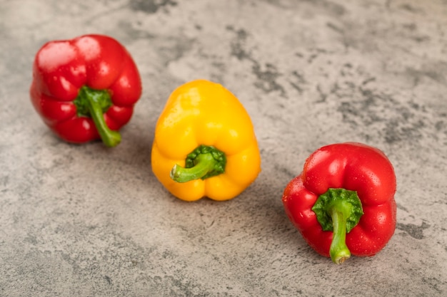 Peperoni dolci freschi colorati posizionati sulla superficie della pietra