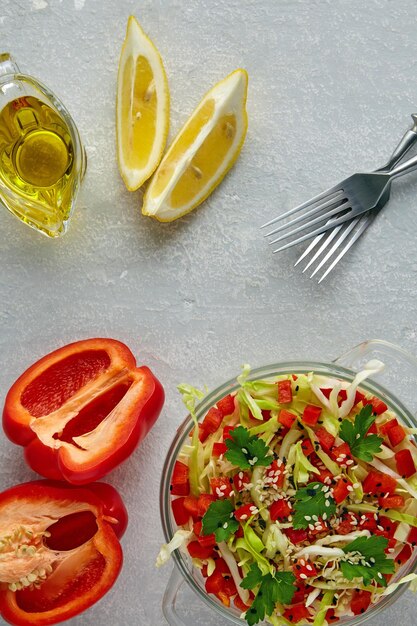 Colorful fresh vegetable salad in a glass bowl on a grey wooden table Vegetarian salad of cabbage sweet pepper and parsley with sesame and cumin seeds and olive oil and lemon dressing