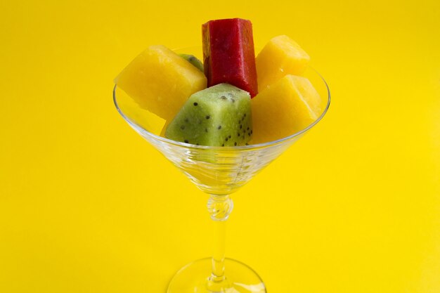 Colorful frozen fruit puree in the martini glass on the yellow background