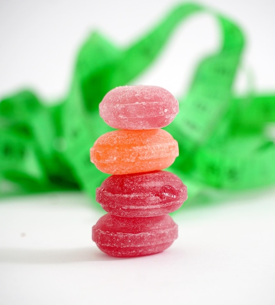 Photo colorful fruit hard candy and tape measure isolated on whitediet concept