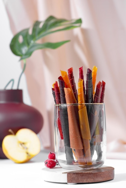 Colorful fruit leather rolls on a plate on light background