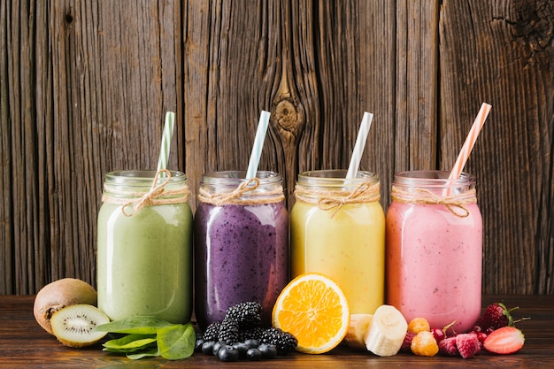 Colorful fruit and smoothies composition on wooden background