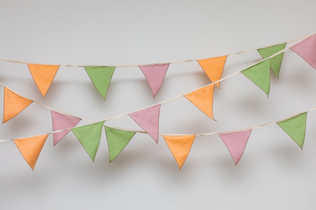 Colorful garland made of triangular textile flags hanging on white wall background