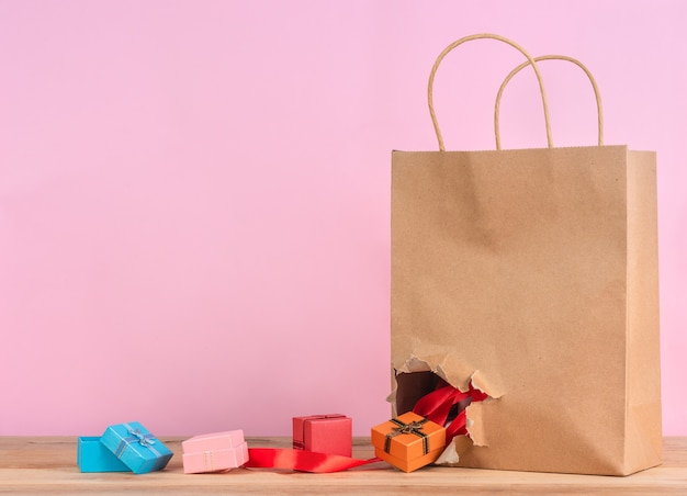 Colorful gift boxes drop out from tearing craft paper bag