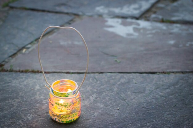 Colorful glass jar with wire handle candle lamp on stone outdoor tile kids activities and handmade