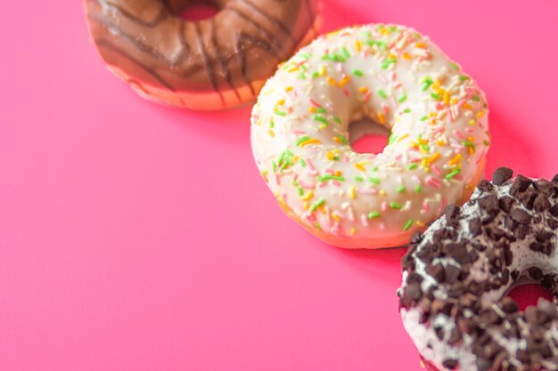 Colorful glazed donuts isolated on a pink background set of three different doughnuts close-up