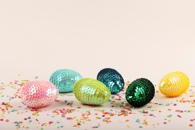 Colorful glossy easter eggs with sequins.Vivid pastry topping on the pastel background.