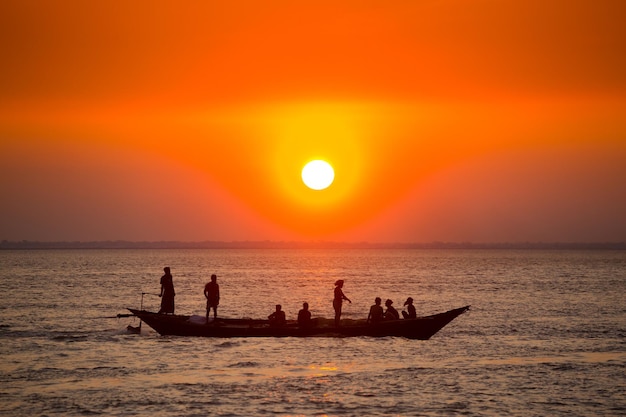 カラフルな金色の海の夕日 漁師は、チャンドプール バングラデシュのチャー サマルジ ビーチで日没時に手動で魚を持って家に帰っています。