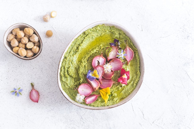 Colorful green hummus with baked radish and flowers