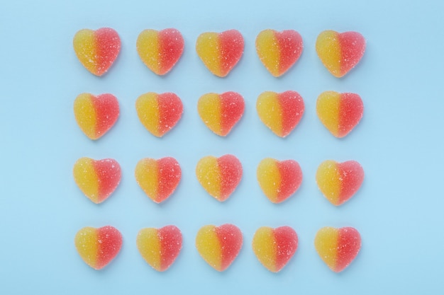 Colorful gummy hearts on blue table. Jelly sweets. 