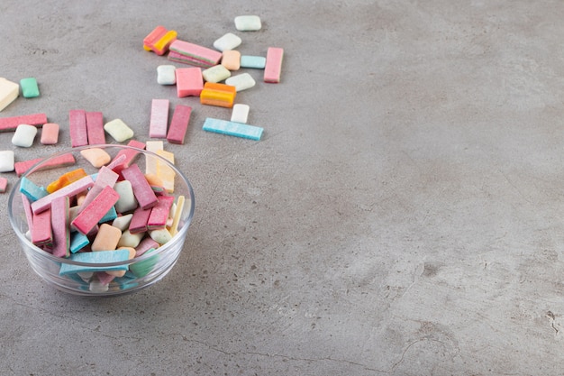 Colorful gums in glass bowls on grey surface