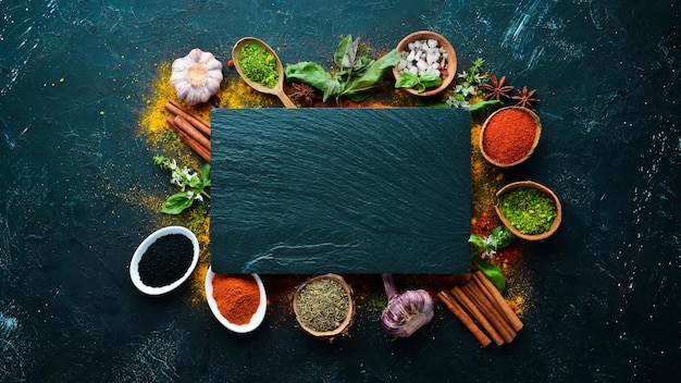 Colorful herbs and spices for cooking Indian spices On a black stone background Top view