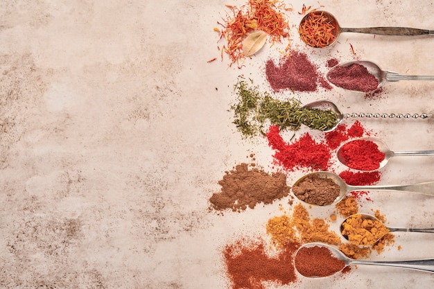Colorful herbs and spices for cooking on light brown stone surface. Top view.