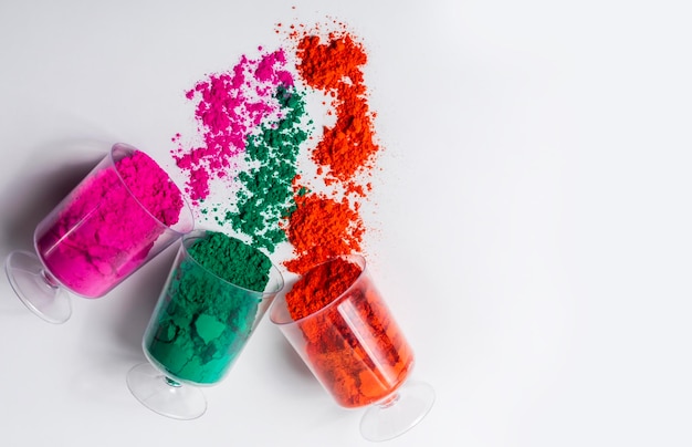 Colorful holi powder in a plastic containers on white background