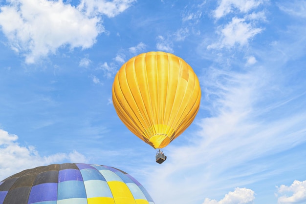 Colorful hot air balloon flying over blue sky with white clouds.