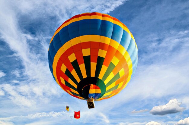 Colorful hot air balloon flying over blue sky with white clouds