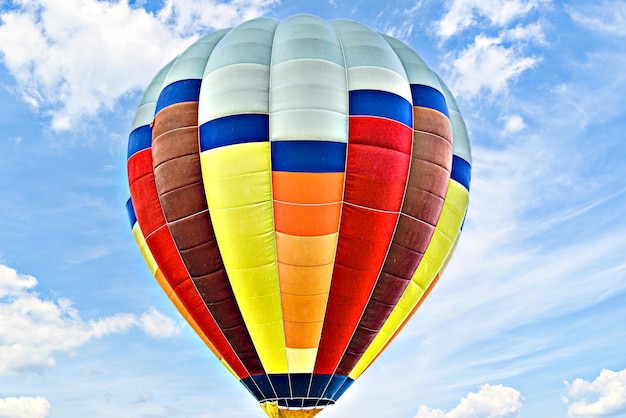 Colorful hot air balloon flying over blue sky with white clouds