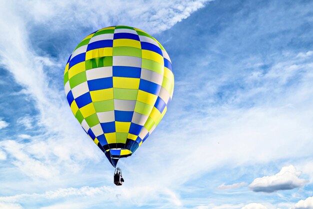 Colorful hot air balloon flying over blue sky with white clouds