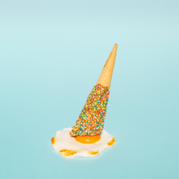 Colorful ice cream cone and poached egg on pastel blue background Minimal summer food concept