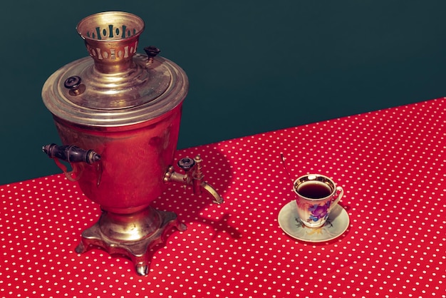 Colorful image of retro tea urn called samovar isolated over green background on pink tablecloth