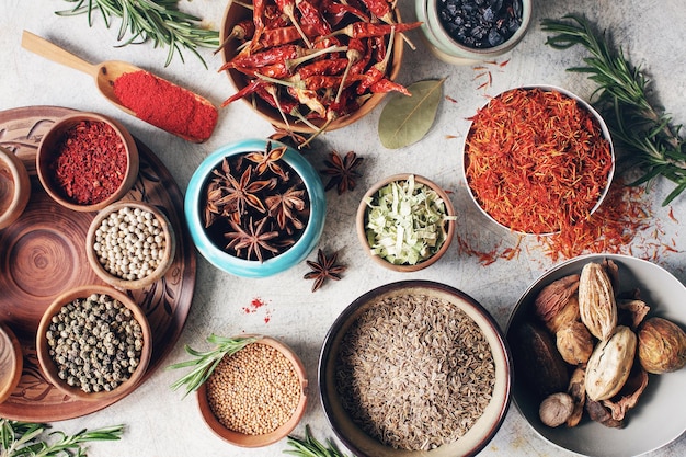 Colorful indian spices and herbs in bowls on light concrete table Healthy lifestyle concept