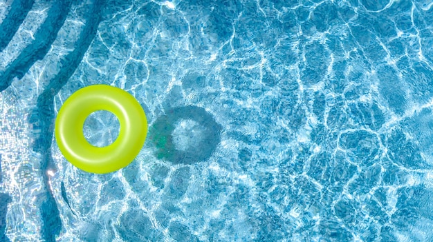 家族での休暇の上からのスイミングプールの水の空中写真のカラフルなインフレータブルリングドーナツのおもちゃ