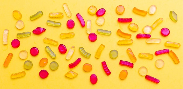 Colorful jelly candies assortment on yellow color background top view