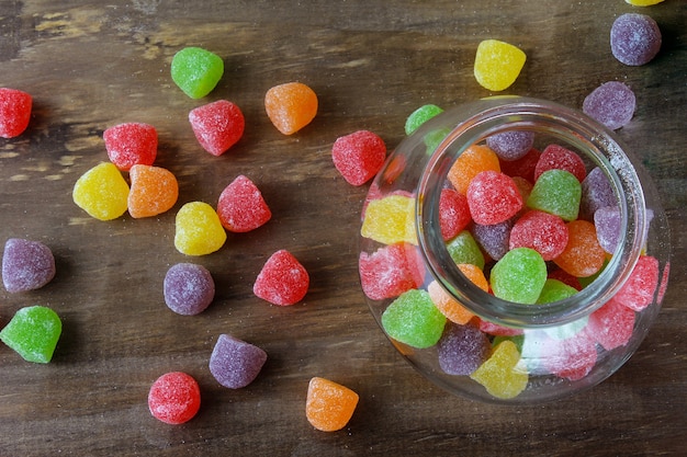 Colorful jelly sugar candies gum arabic sweet on wooden confectionery table. Top view