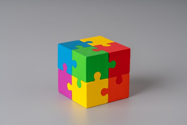 Colorful jigsaw puzzle cube on gray background