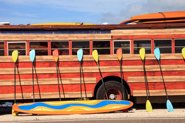 Foto colorati kayak e paddleboard appoggiati contro un autobus hippie in stile legnoso a nassau bahamas