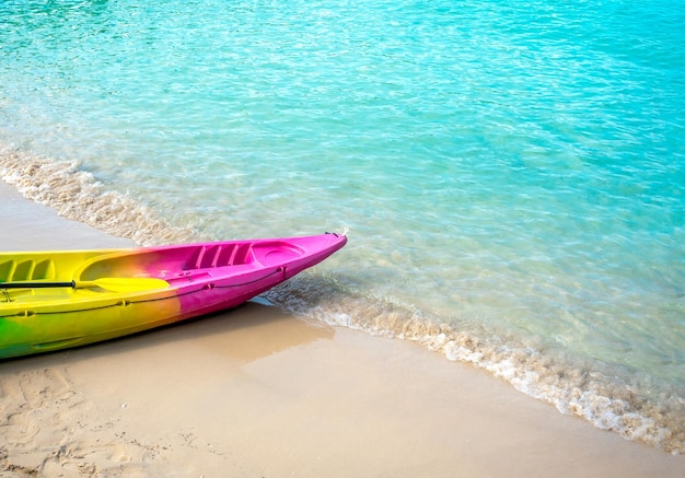 Kayak colorato con nessuno sulla spiaggia sabbiosa pulita e sfondo blu del mare con attrezzature per attività di spazio copia prepararsi per gli ospiti dell'hotel o del resort in viaggio per le vacanze estive