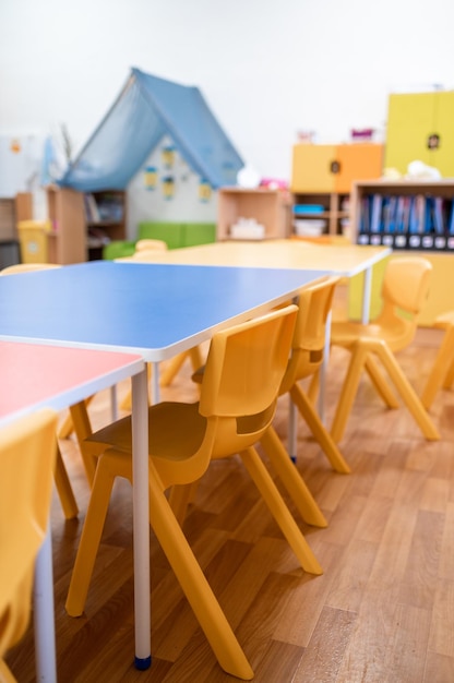 Foto classe di scuola materna colorata senza sedia da scrivania per l'educazione scolastica dei bambini giocattolo e decorazione sulla parete di fondo infanzia